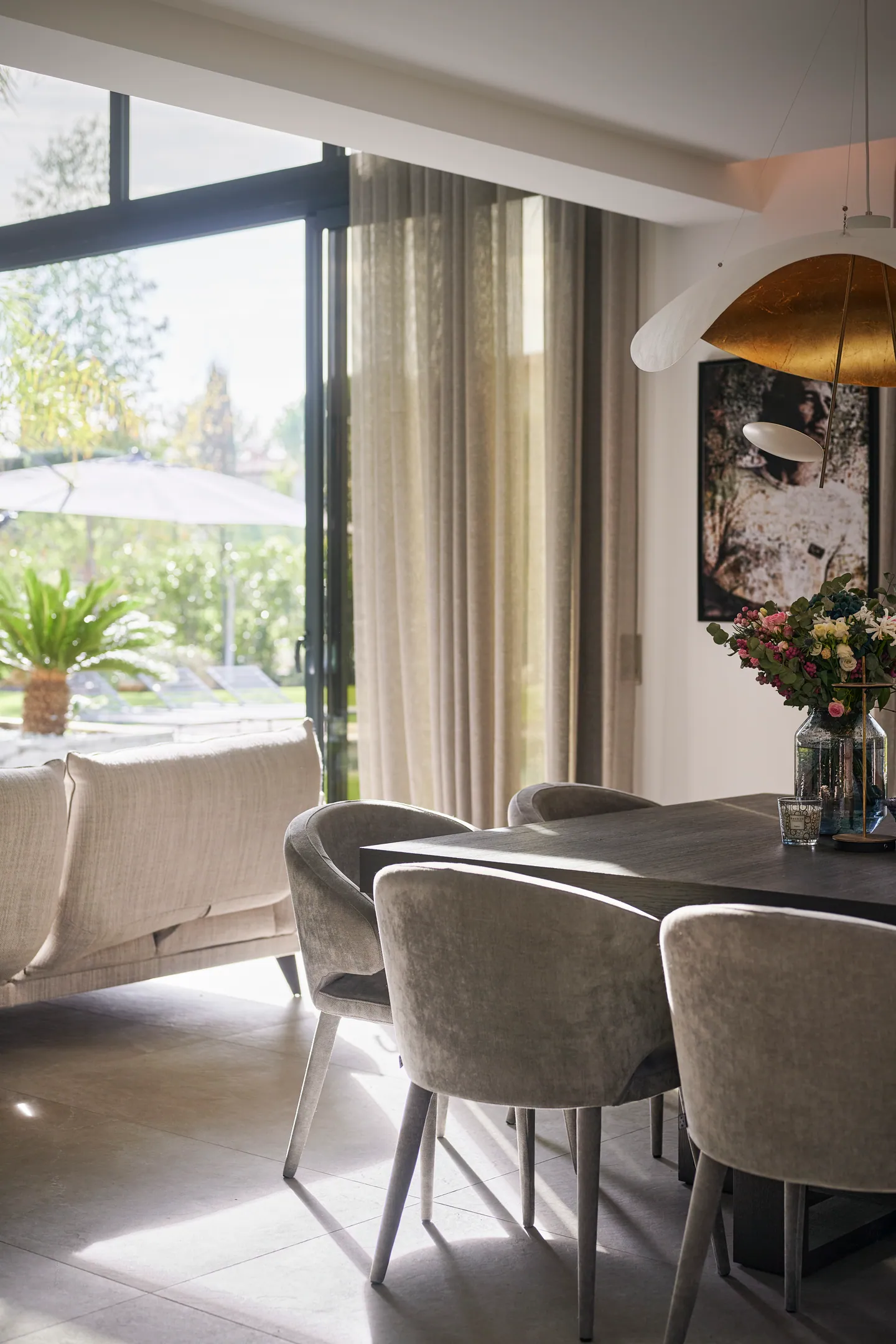 Coin repas de la villa Anse d’argent baigné de lumière, suspension dorée, bouquet et baie ouverte sur la terrasse