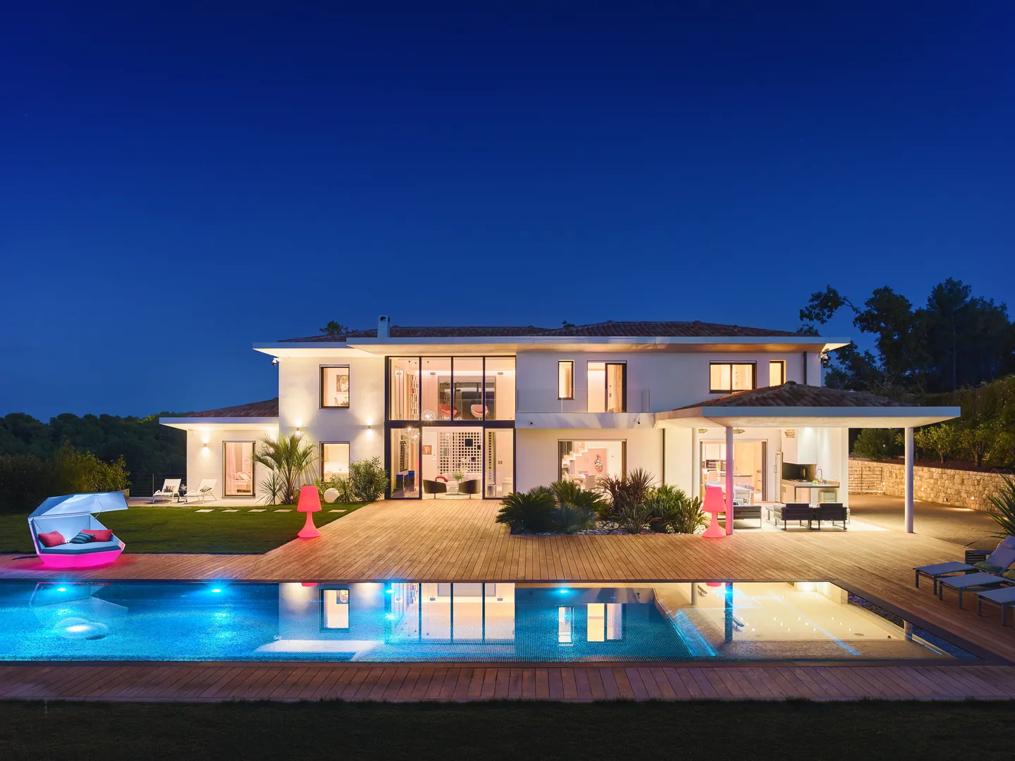 Villa illuminée à la nuit tombante, reflets dans la piscine